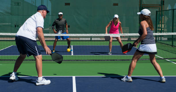 Pickleball players on court with close up of paddle